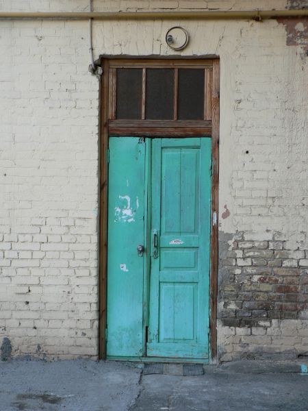Old, narrow wooden door painted in vibrant blue color with slightly worn surface.